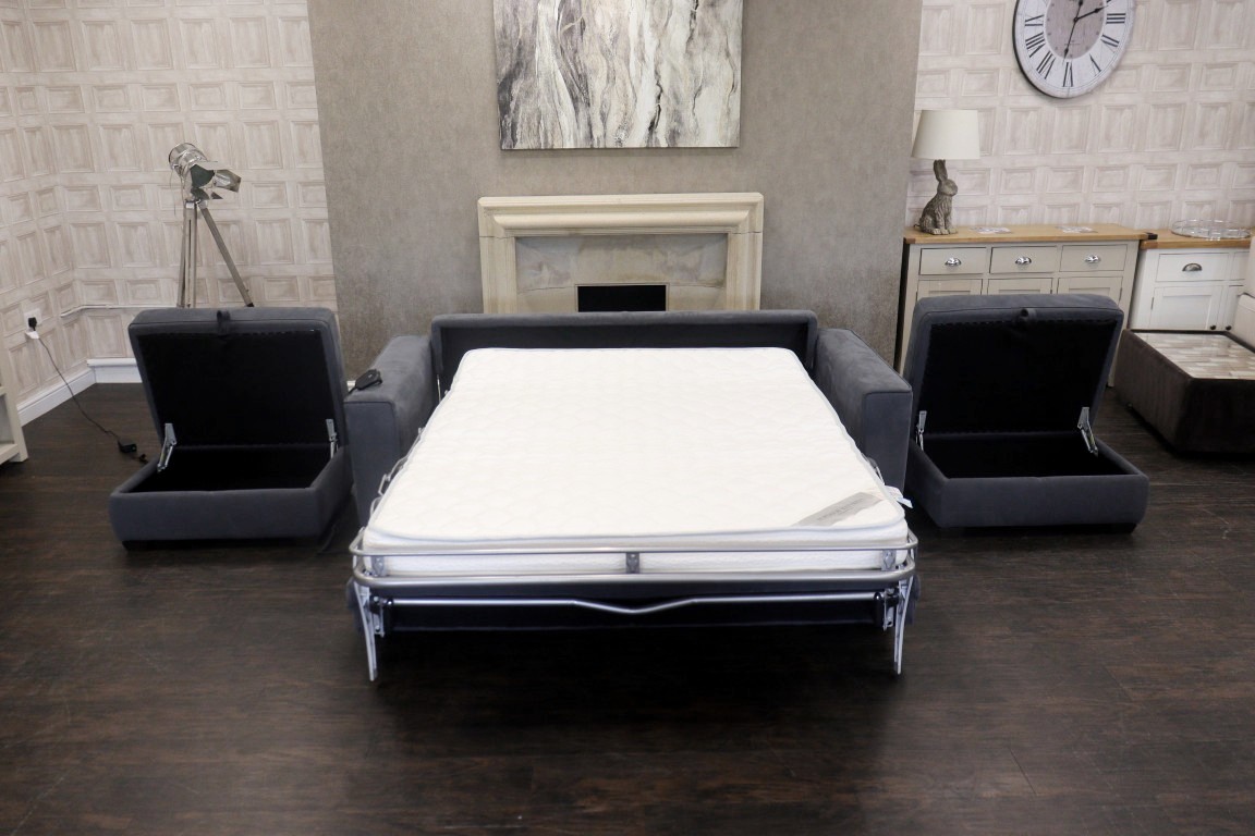 Charcoal grey fabric sofa bed opened out with matching storage stools, ideal for maximising guest capacity.