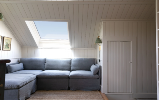 Low-profile grey fabric corner sectional sofa positioned under low cottage ceiling.