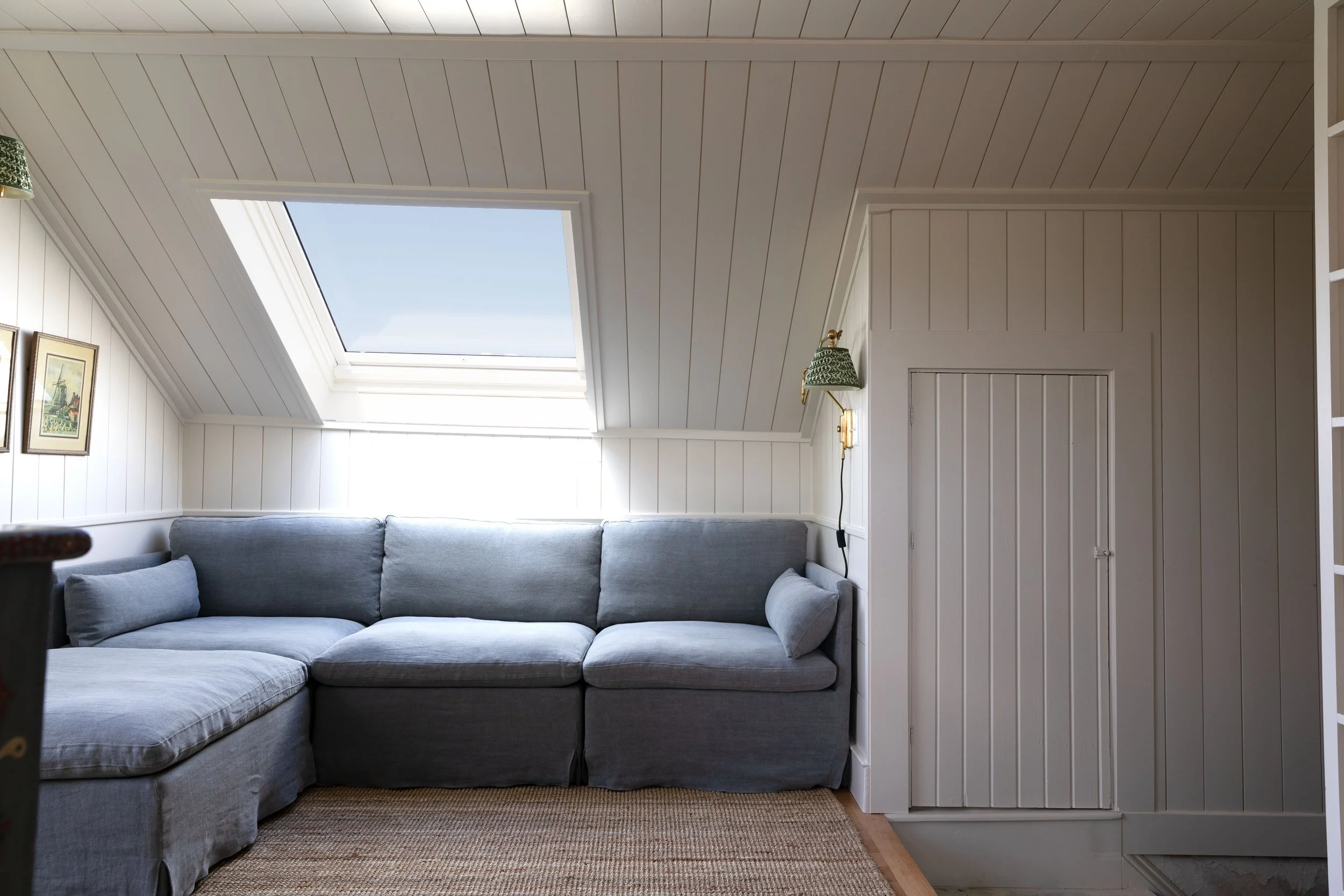 Low-profile grey fabric corner sectional sofa positioned under low cottage ceiling.